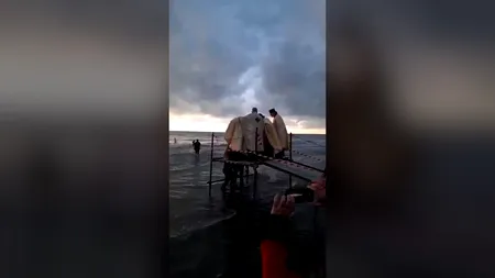 Moment inedit la malul mării: Un preot a căzut în apă în timpul slujbei de Bobotează | VIDEO