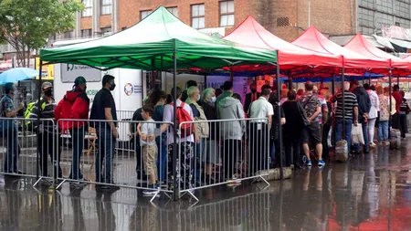 Vaccinarea cu mici și muștar continuă la centrul din Piața Obor. Românii au așteptat în ploaie să-și primească porția și doza (FOTOREPORTAJ)