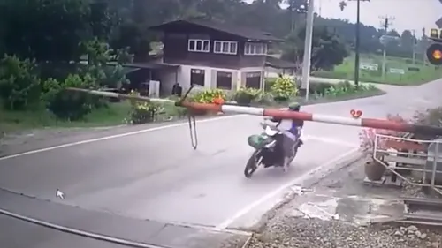 O motociclistă, la câteva secunde de o moarte cumplită. Femeia nu a văzut bariera și s-a răsturnat pe calea ferată. VIDEO cu momentul în care este salvată