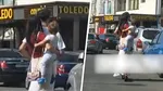 O femeie merge pe trotineta electrică, printre mașini, cu un bebeluș în brațe
