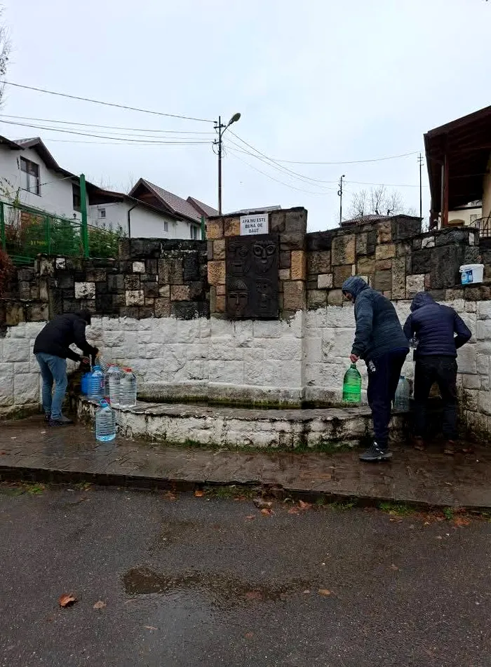 Câțiva localnici din Prahova se străduiesc să ia apă în sticle din plastic de la un izvor cu apă nepotabilă (Foto: DSP Prahova)