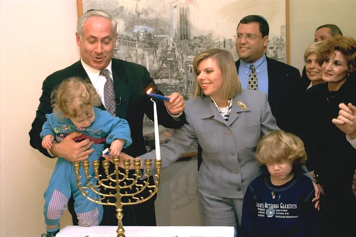 Yair Netanyahu, într-o fotografie când din copilăria sa: El este ținut în brațe de tatăl său, Benjamin Netanyahu, care aprinde menorah, un sfeșnic evreiesc 