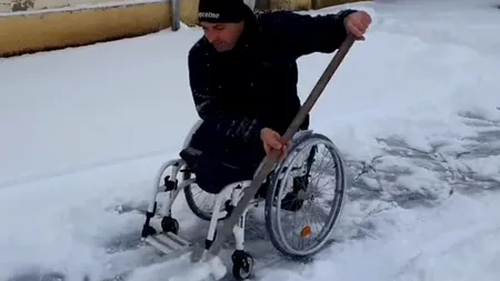 Imagini emoționante! Un bărbat în scaun cu rotile deszăpezește trotuarul din fața casei - VIDEO
