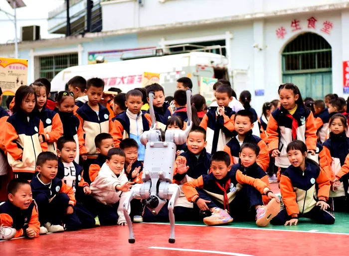 Elevii unei școli din provincia Guizhou urmăresc un robo-câine care face acrobații. 