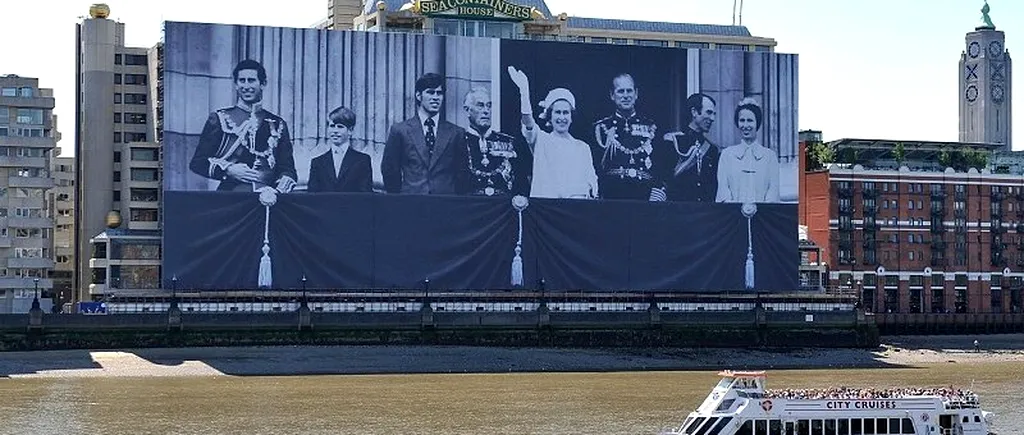 Un banner uriaș cu imaginea Familiei Regale britanice, desfășurat  pe cheiul Tamisei