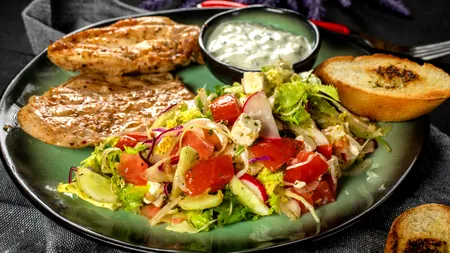 Salată grecească de vară sub 600 de calorii. Rețetă aromată cu pui, cartofi crocanți și sos tzatziki