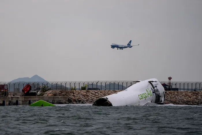 October 20, 2025, Hong Kong, Hong Kong: A cargo plane lies partially in the sea after veering off the runway while landing at Hong Kong International Airport in Hong Kong. The cargo plane has skidded off a runway at Hong Kong International Airport and landed in the sea, killing two persons. The Emirates flight EK9788, a Boeing 747-481 owned by Turkish cargo airline Air ACT, was arriving from Dubai at about 03:50 local time (19:50 GMT) when it hit a vehicle on the north runway. Two airport ground staff fell into the sea, a statement from the Civil Aviation department says. They were rescued but later died in hospital, according to local media including public broadcaster RTHK citing police. Four crew members onboard the plane survived and were taken to hospital.,Image: 1046861938, License: Rights-managed, Restrictions: , Model Release: no, Credit line: Vernon Yuen / Zuma Press / Profimedia