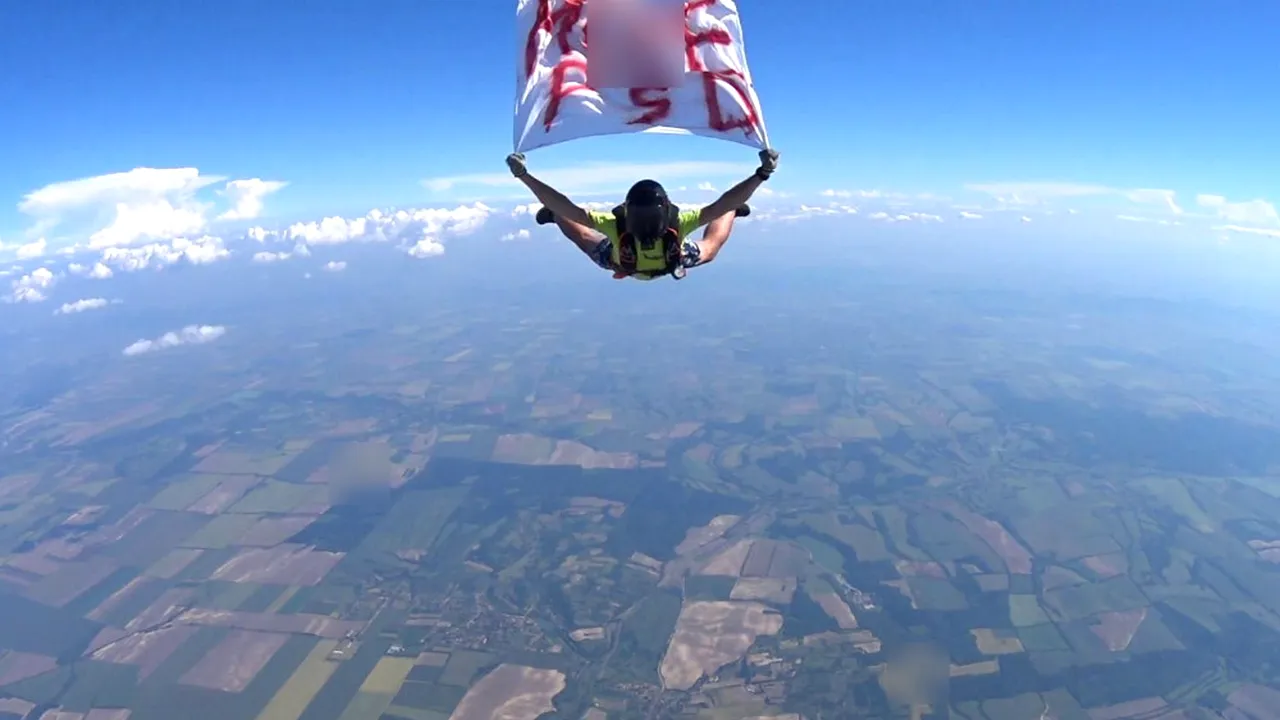 Mesajul M..EPSD coboară din cer. Un parașutist a sărit de la mii de metri cu un banner anti-PSD. Saltul, realizat ÎN AFARA României