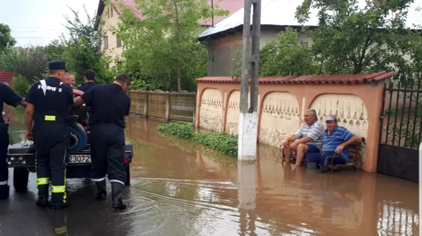 Fotografia zilei, din Teleorman: Localnicii stau pe bancă privind cum pompierii scot apa din comună. Revolta oamenilor pe rețelele de socializare