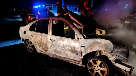 FOTO | O mașină în care se afla o tânără de 21 de ani a ars complet, după ce șoferița a intrat frontal într-un copac