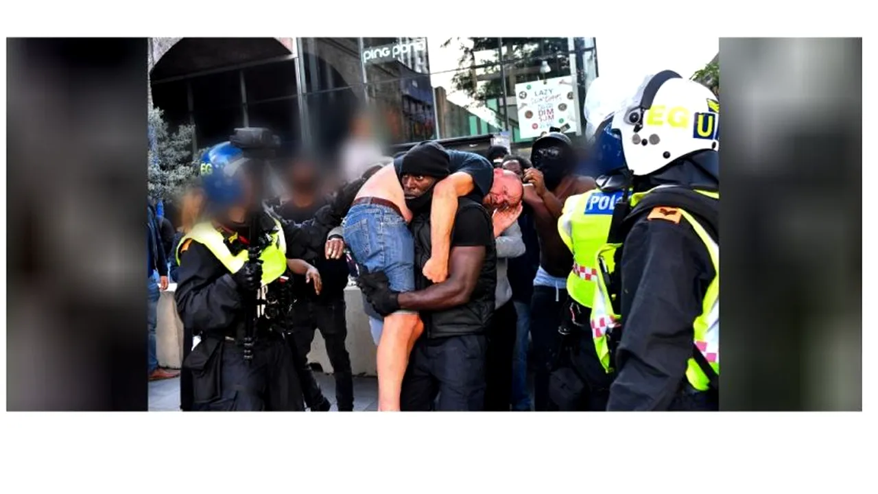 PROTESTE. Un bărbat de culoare, surprins în timp ce salvează un protestatar alb