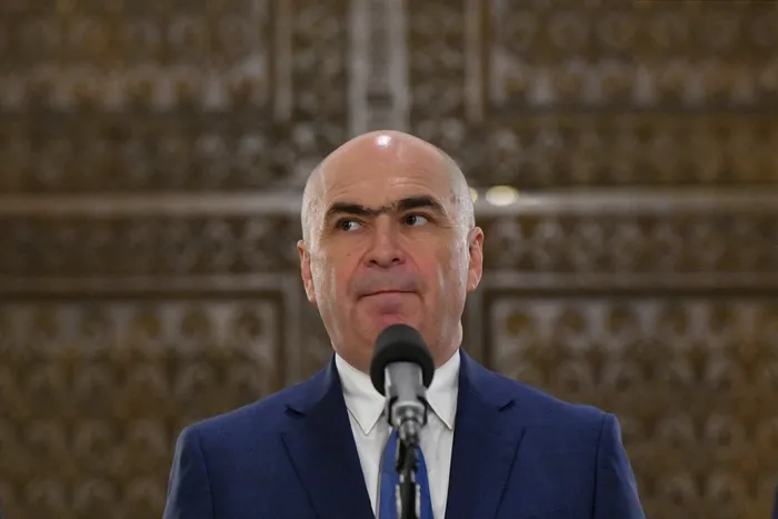Bolojan le mulțumește oamenilor că au sărăcit ca să reducă deficitul. Niciun cuvânt despre scăderea taxelor pentru multinaționale