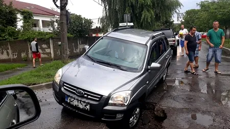 Un șofer a rămas cu mașina suspendată într-o GROAPĂ URIAȘĂ din asfalt