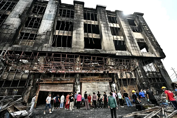 Localnicii curăță dărâmăturile unui supermarket incendiat în timpul protestelor din Kathmandu.