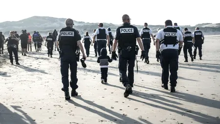 Momentul în care polițiștii francezi intră în apă și găuresc cu cuțitele o barcă de cauciuc plină cu IMIGRANȚI, surprins de reporteri