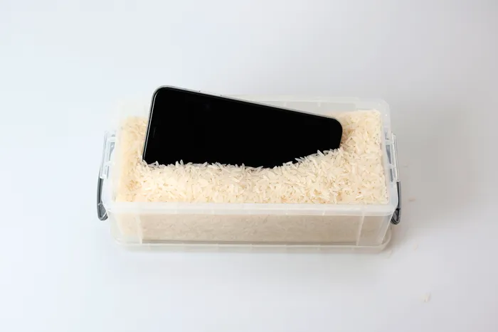 Tehnica orezului: telefonul așezat printre boabele de orez pentru a absorbi umezeala / foto: Shutterstock