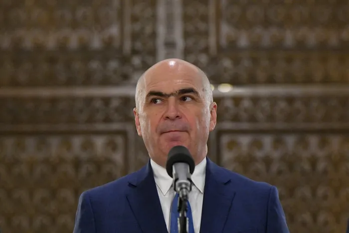 Bolojan le mulțumește oamenilor că au sărăcit ca să reducă deficitul. Niciun cuvânt despre scăderea taxelor pentru multinaționale